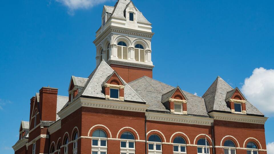 A large brick building with a prominent tower and arched windows.