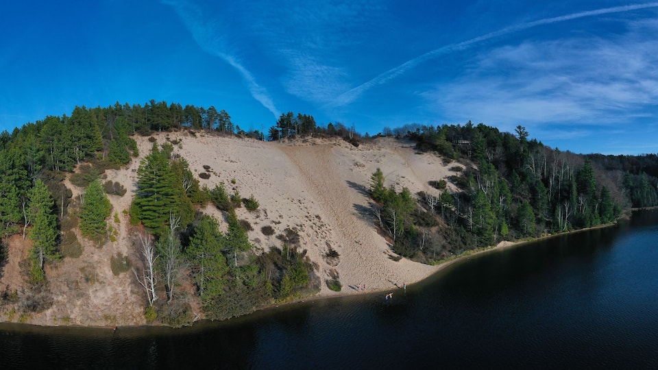 An island surrounded by a lake with dense forests and a clear sky.