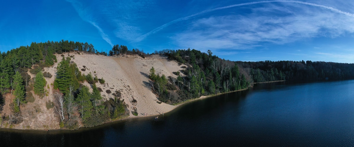 An island surrounded by a lake with dense forests and a clear sky.