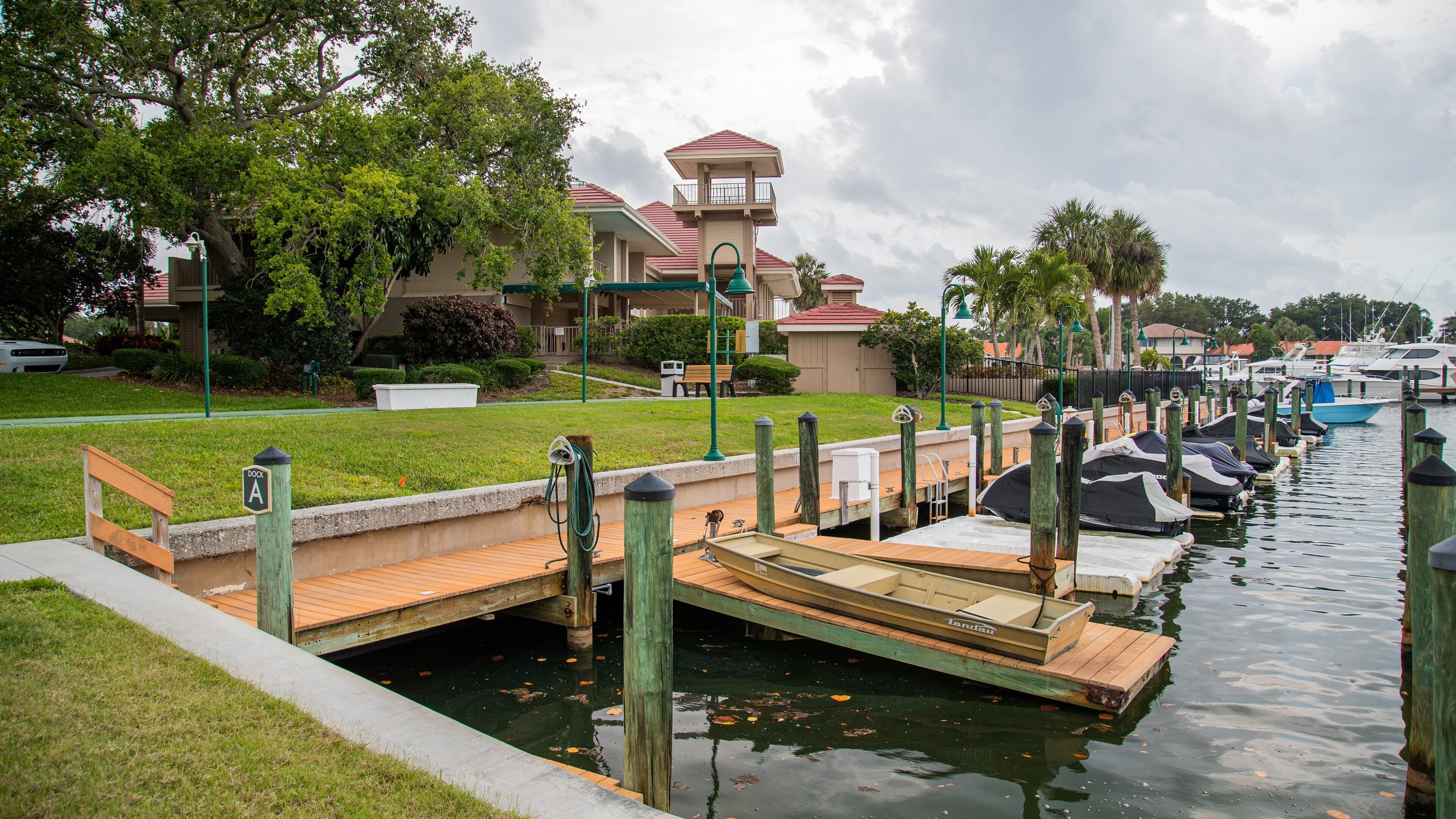 A marina with docked boats, a wooden bridge, and a building with a red roof.