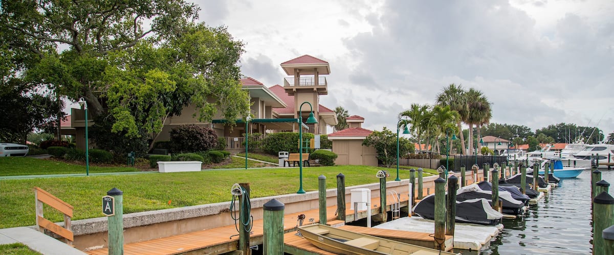 A marina with docked boats, a wooden bridge, and a building with a red roof.