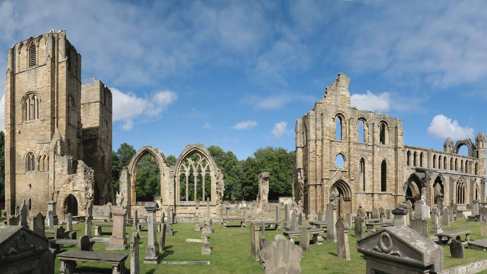 A historic church with Gothic architecture and a cemetery in the foreground.