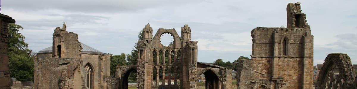 An ancient ruined church with Gothic architecture, including pointed arches and a large circular window.