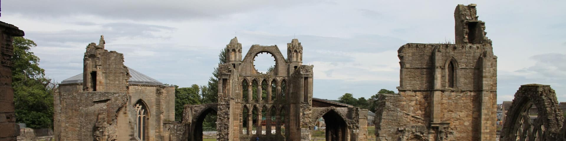 An ancient ruined church with Gothic architecture, including pointed arches and a large circular window.