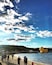 A beach with people, a large yellow duck sculpture, and a clear sky with clouds.