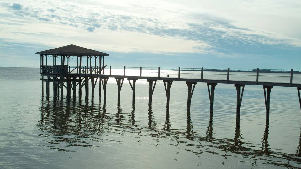 A wooden pier extending into calm water with a covered shelter at the end.