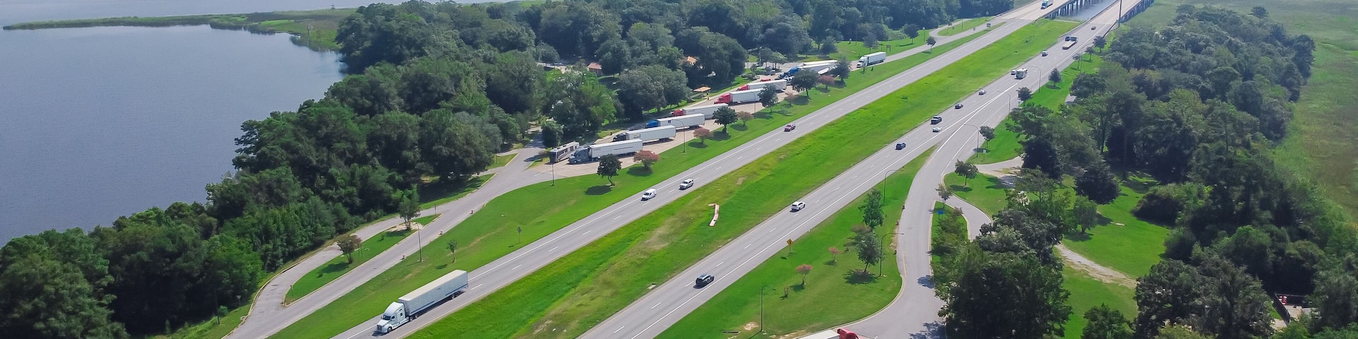 Jackson County Rest Area West rest area with Pascagoula River bridge, large parking lots semi-trucks, cargo trailers along Interstate 10 (I-10) floodplain in Gautier, Lower Mississippi