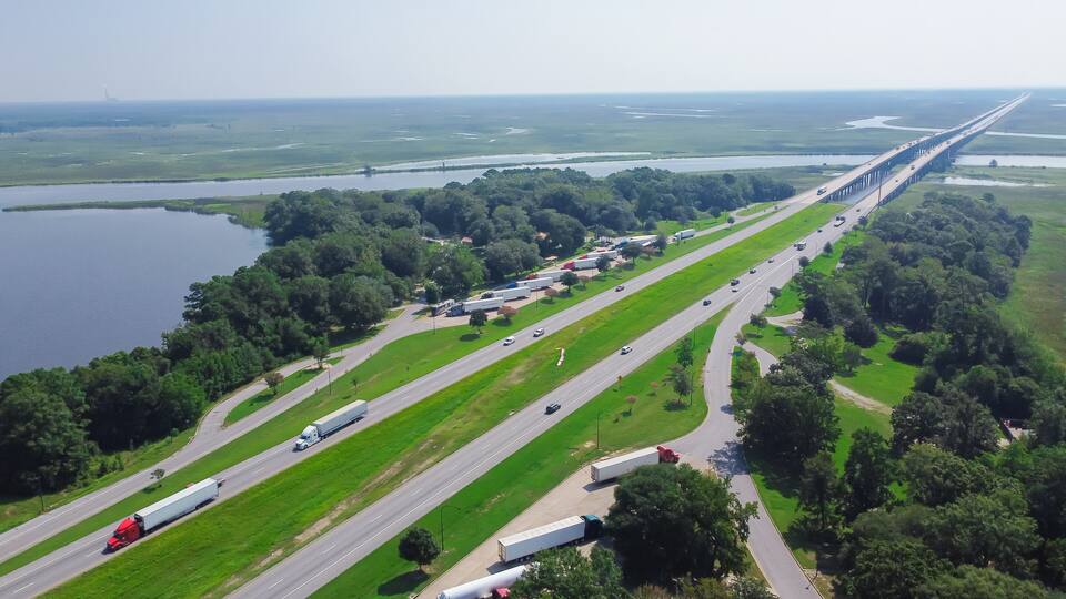 A highway with multiple lanes, a bridge, and a large body of water.