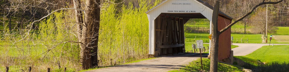 A covered bridge with a sign reading '1909 PHILLIPS BRIDGE' and a 'No Parking' sign.