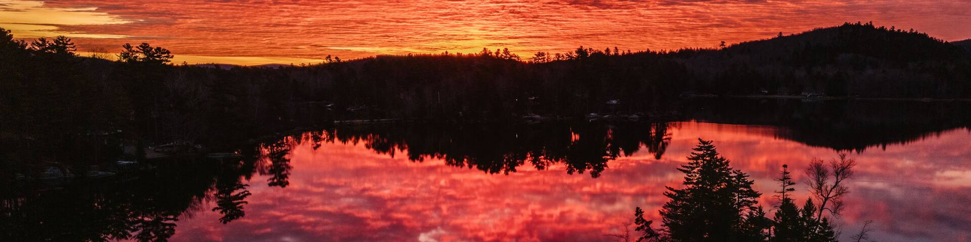 Sunrise reflected in peaceful lake with island, Phillips Lake, Maine
