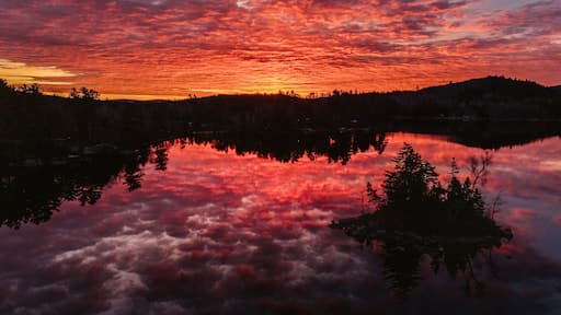 Sunrise reflected in peaceful lake with island, Phillips Lake, Maine