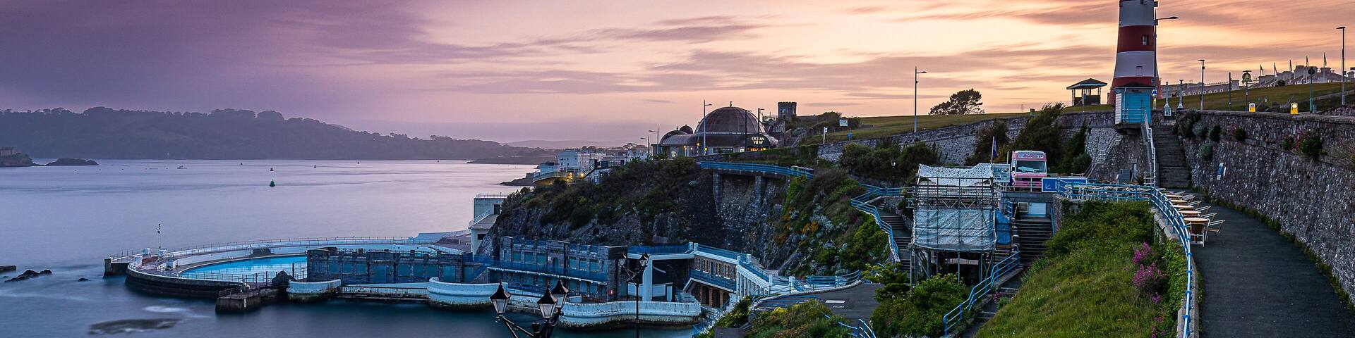 A coastal lighthouse, a large domed building, and a curved pier.