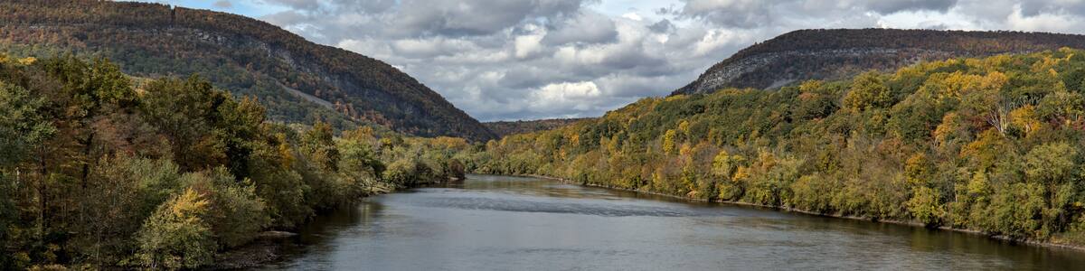 A river winding through a valley with autumn-colored trees and hills in the background.