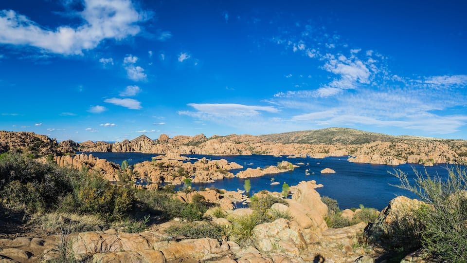 A rocky landscape with a large body of water surrounded by hills and sparse vegetation.