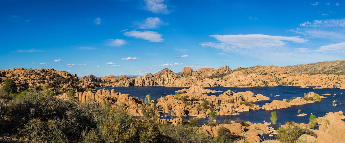 A rocky landscape with a large body of water surrounded by hills and sparse vegetation.