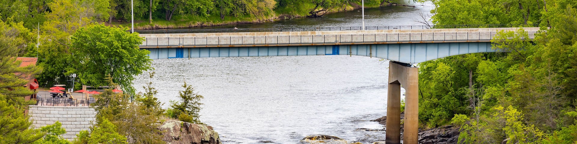 A river with a bridge, rocky outcrops, and lush greenery.