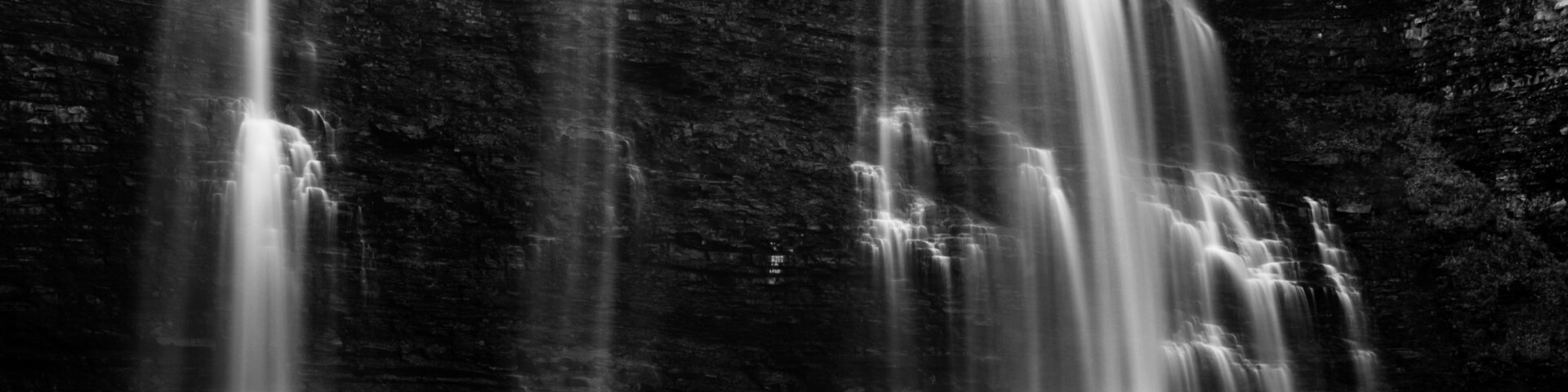 Una cascada en varios niveles que se precipita sobre un acantilado rocoso hacia una masa de agua.
