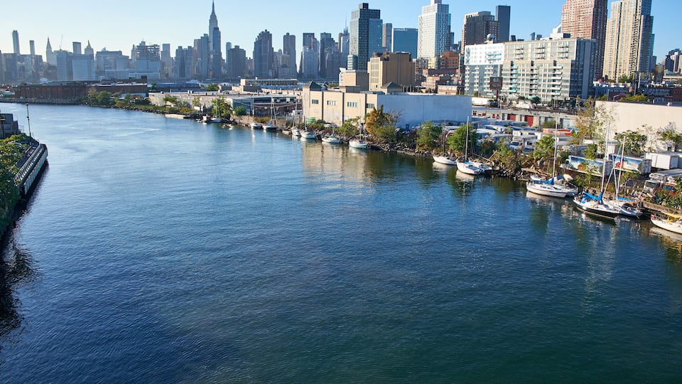 A river with boats, a city skyline, and buildings along the riverbank.