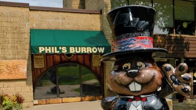 A large bear statue in front of PHIL'S BURROW restaurant.