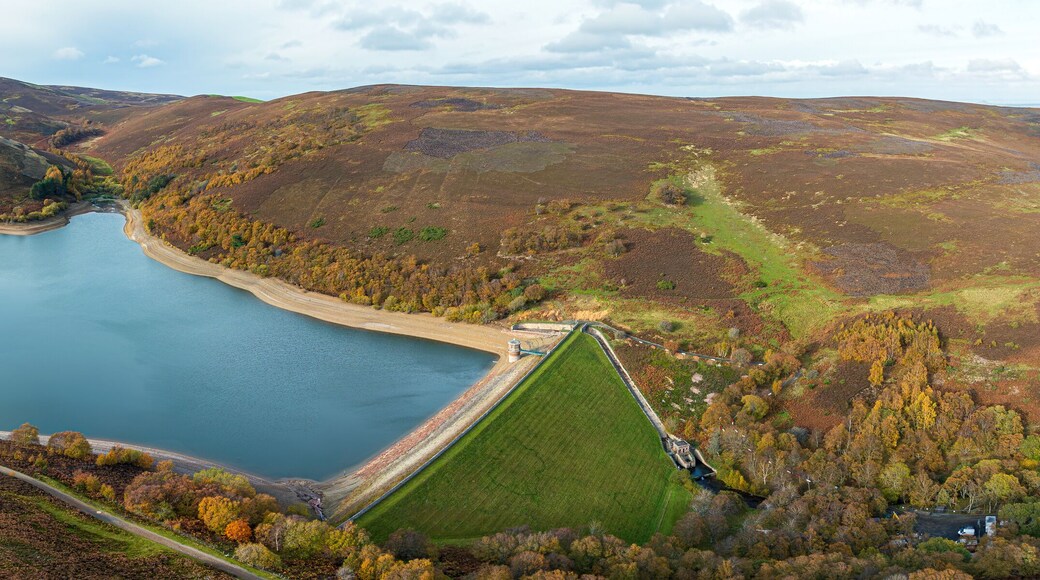 Aerial view of a reservoir's tranquil waters reflect the sky, embraced by the rugged hillsides and vibrant autumn foliage, Haddington, Scotland, United Kingdom.