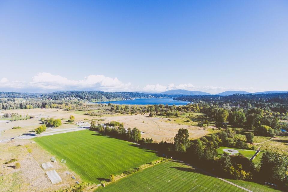 A large green field, a lake, and distant mountains.