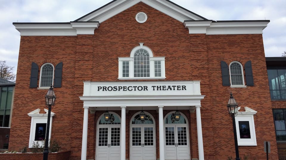 A brick building with a white facade and the name "Prospector Theater" above the entrance.