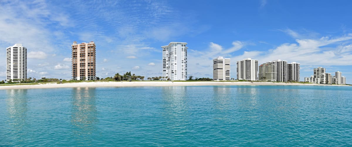 A coastal cityscape with high-rise buildings and a sandy beach.