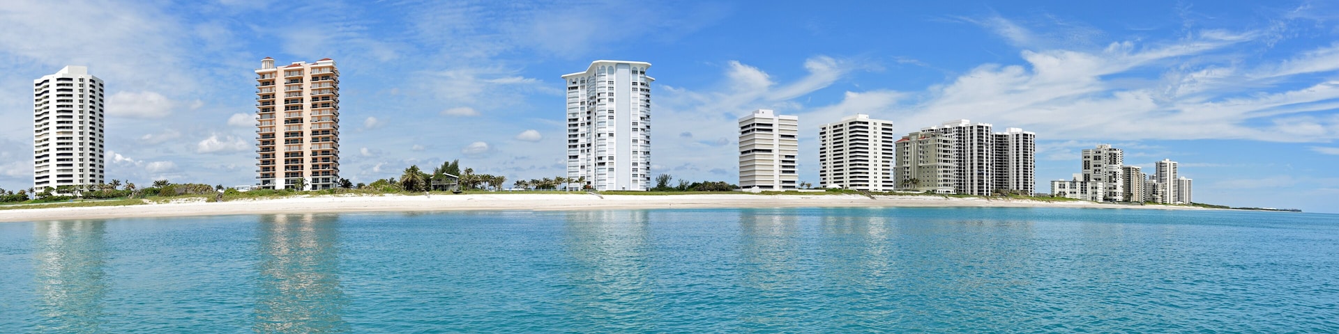 A coastal cityscape with high-rise buildings and a sandy beach.