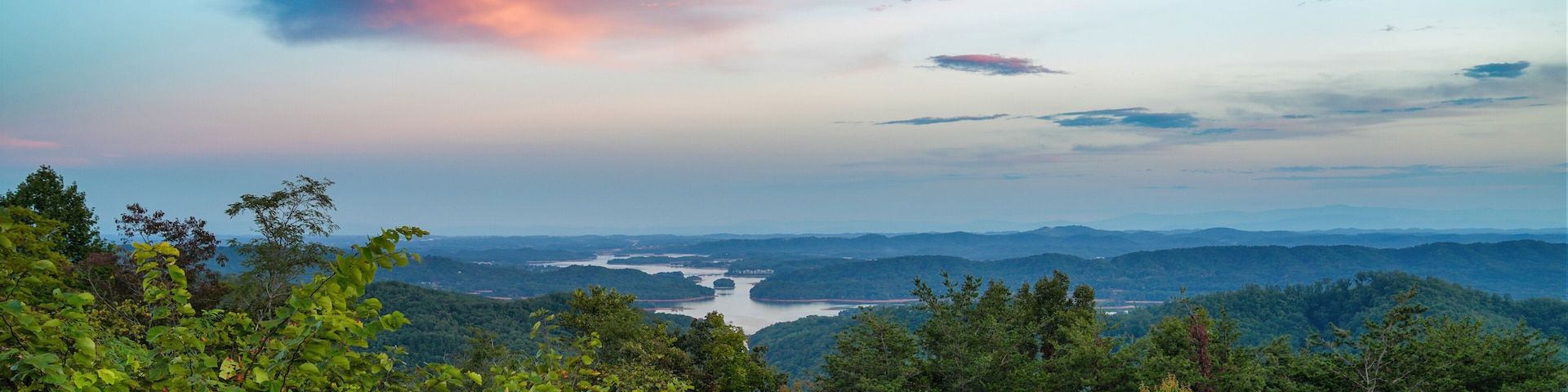 Un paisaje montañoso con vegetación verde exuberante y un río a lo lejos.