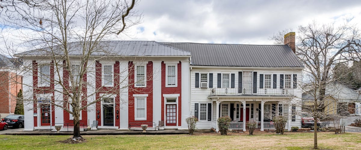A large, two-story red and white house with a porch and a brick chimney.