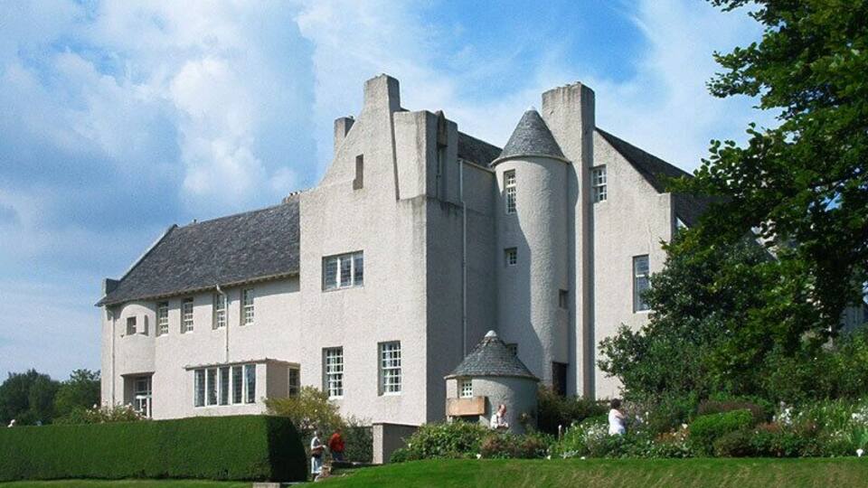 A large, white, castle-like building with multiple towers and a well-maintained lawn.