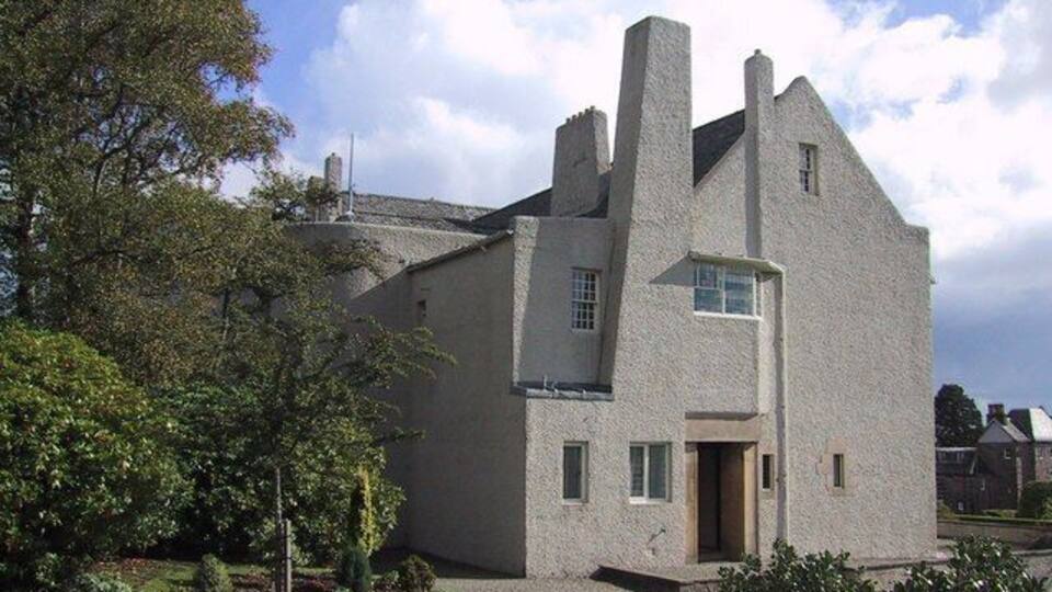 A modern house with a unique architectural design, featuring a steep roof and multiple chimneys.