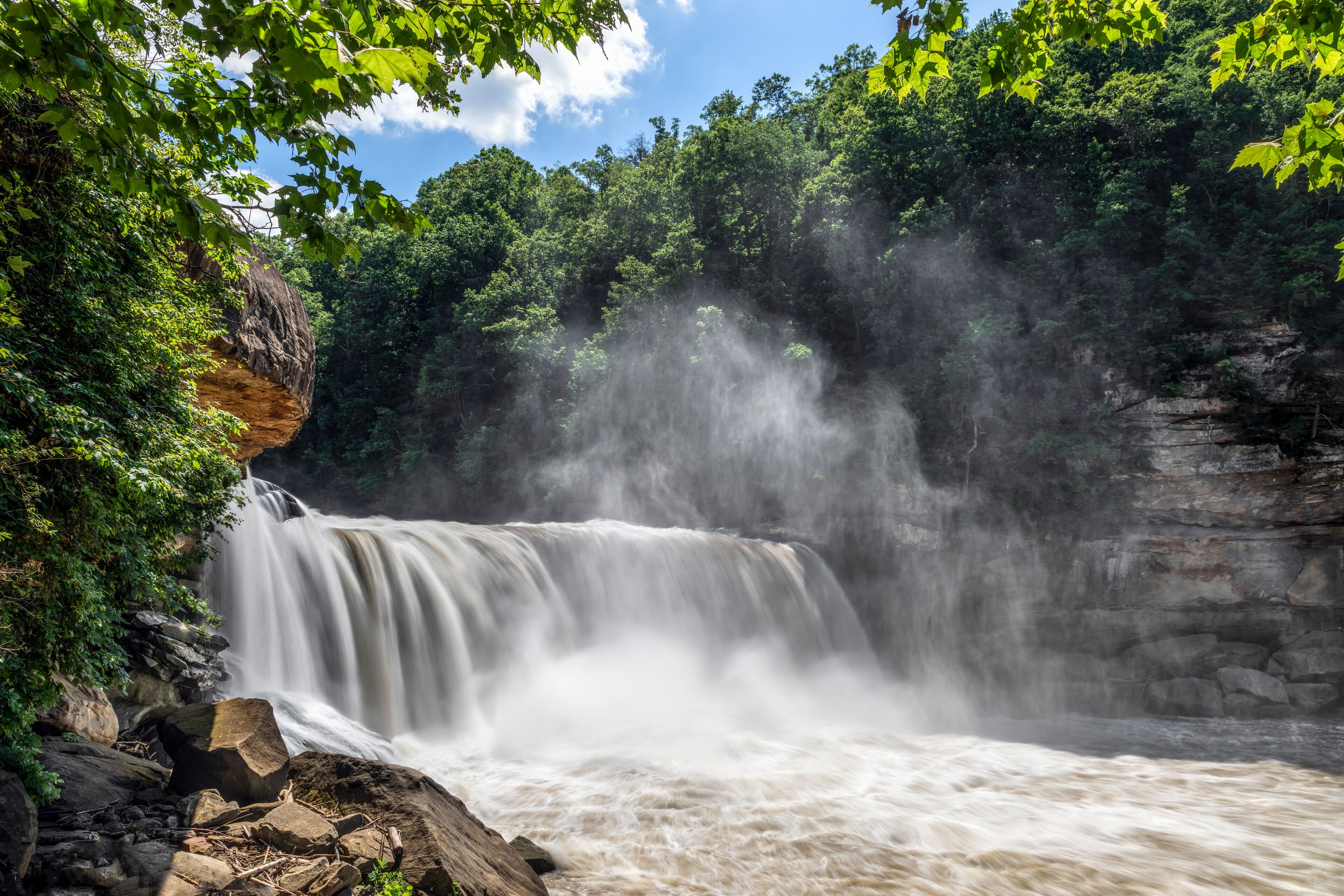 A waterfall cascading over a rocky cliff surrounded by dense green foliage.