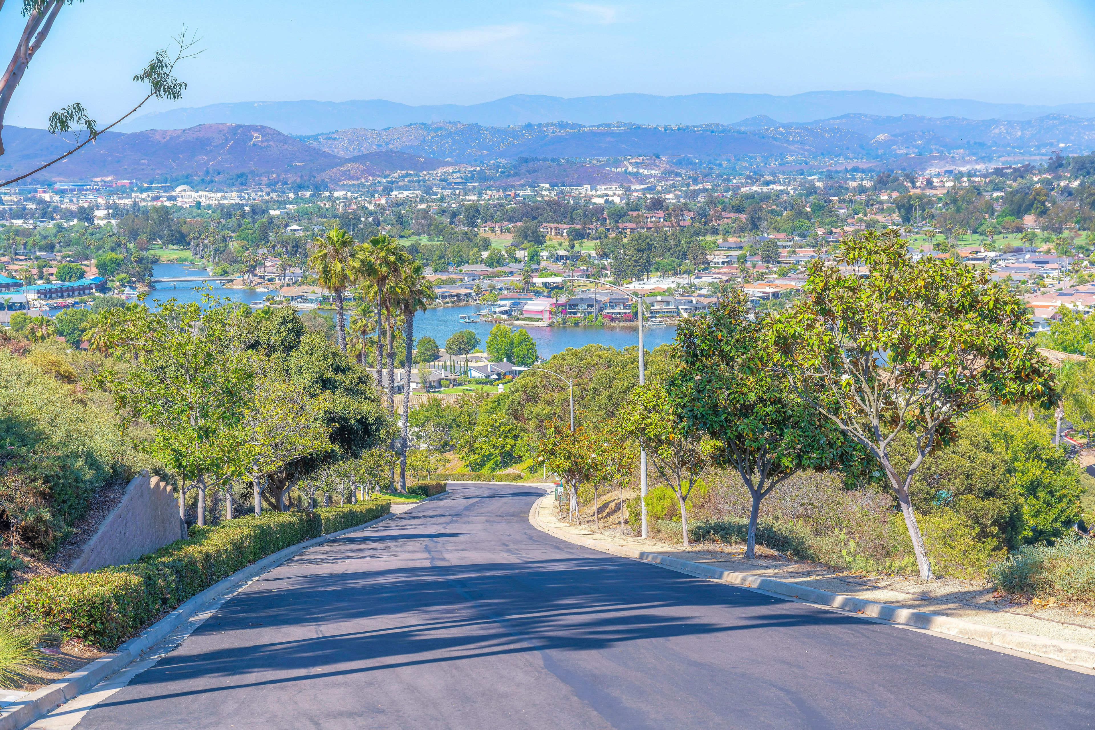 Downhill asphalt road with a view of the Lake San Marcos and mountains at San Diego, California