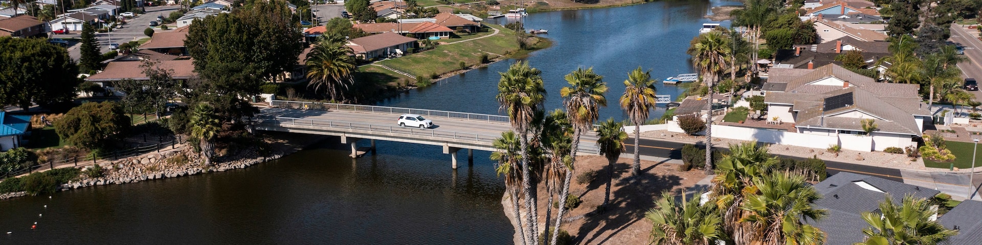 Ein Wohngebiet mit einer Brücke über einem Fluss, umgeben von Häusern und Palmen.