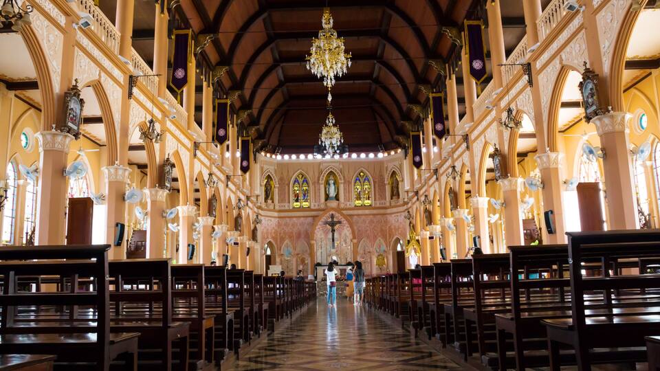 An ornate church interior with high ceilings, chandeliers, and rows of pews.