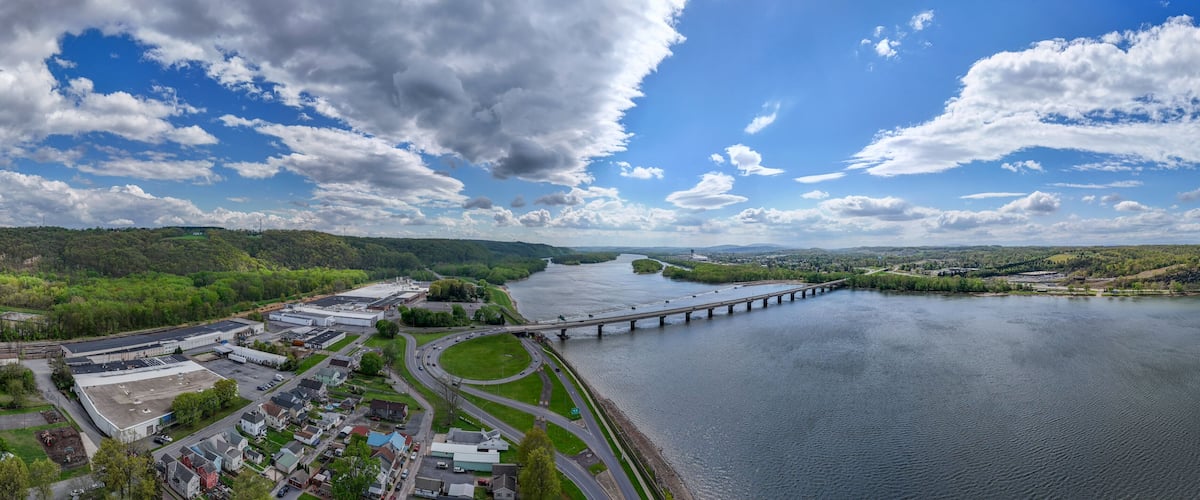 A river with a bridge, industrial buildings, and a green landscape.