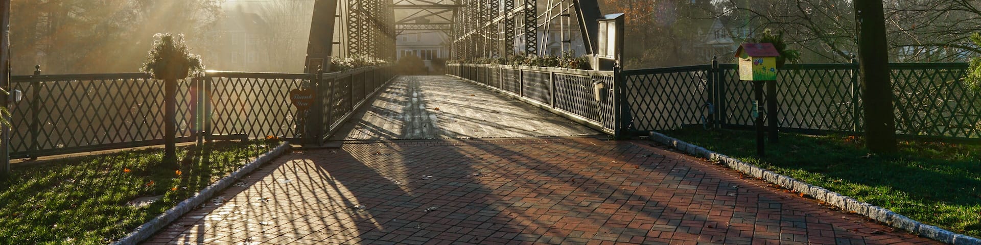 A metal bridge with a sign that reads 'Thank You' and a birdhouse on the right.