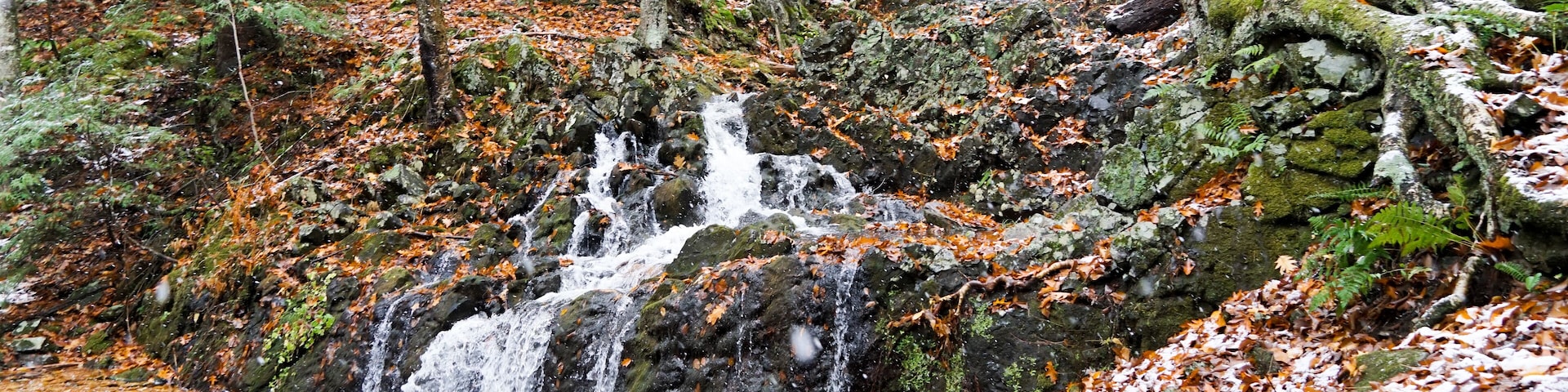 Northgate Falls in Simsbury Connecticut. A beautiful autumn waterfall spills into a stream.