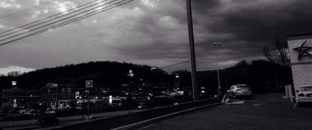 A cloudy sky over a town with power lines and a few buildings in the background.