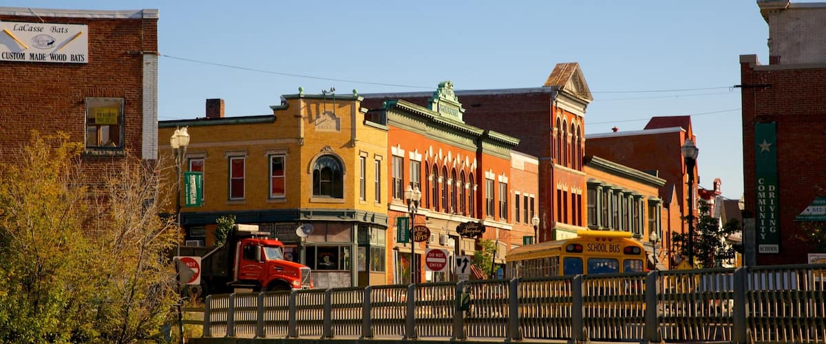 A street scene with a school bus, a red truck, and various buildings including a brick building with a sign for LaCasse Bats.