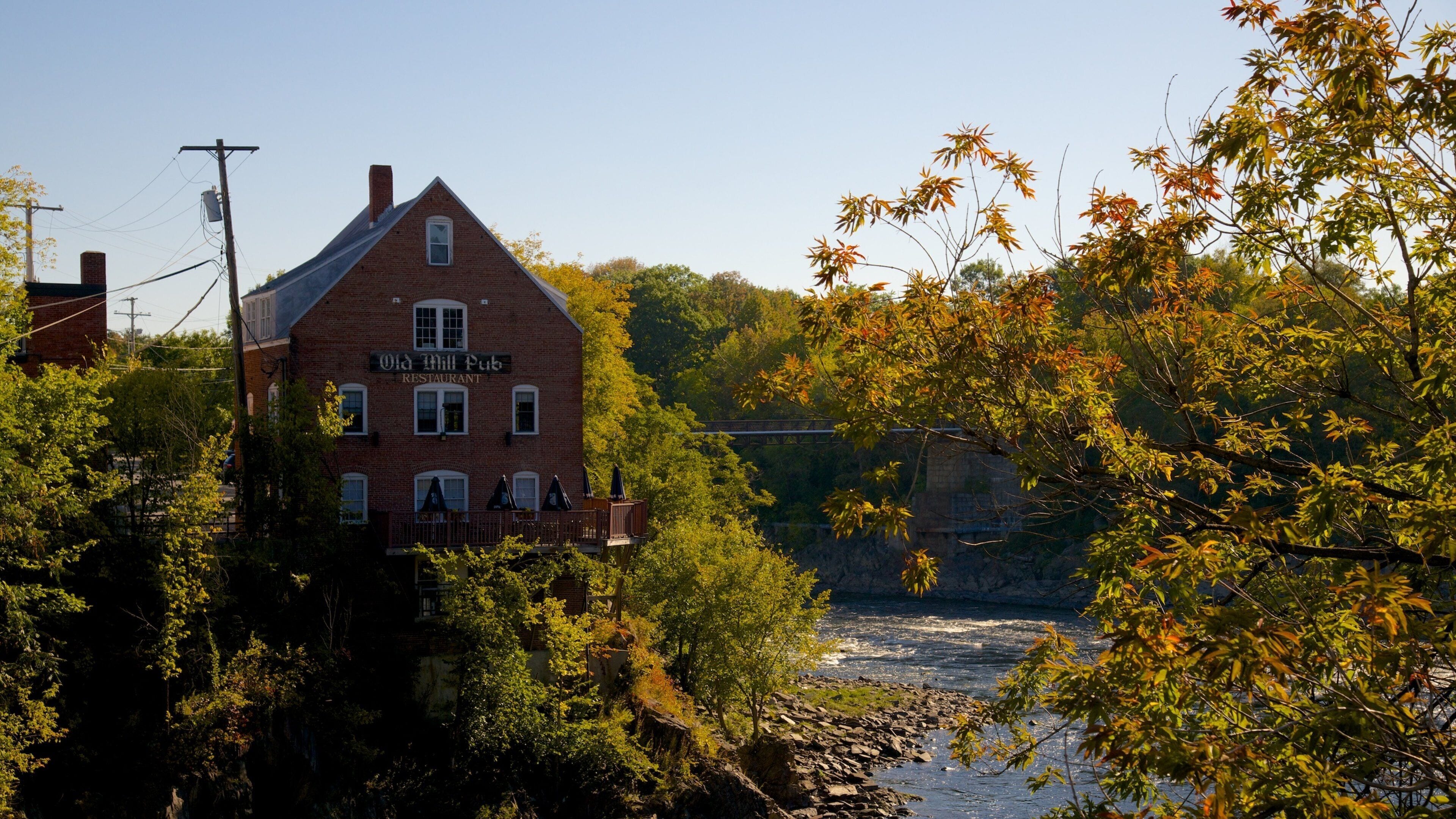 A brick building labeled "Old Mill Pub Restaurant" with a river and trees in the background.