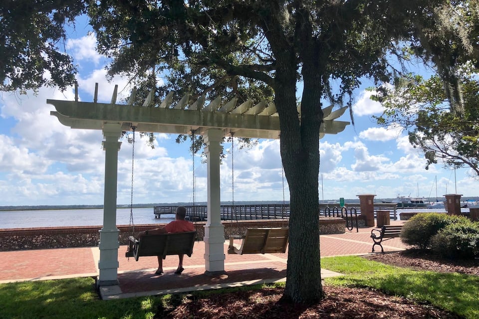 A park with a swing set and a gazebo overlooking a waterfront.