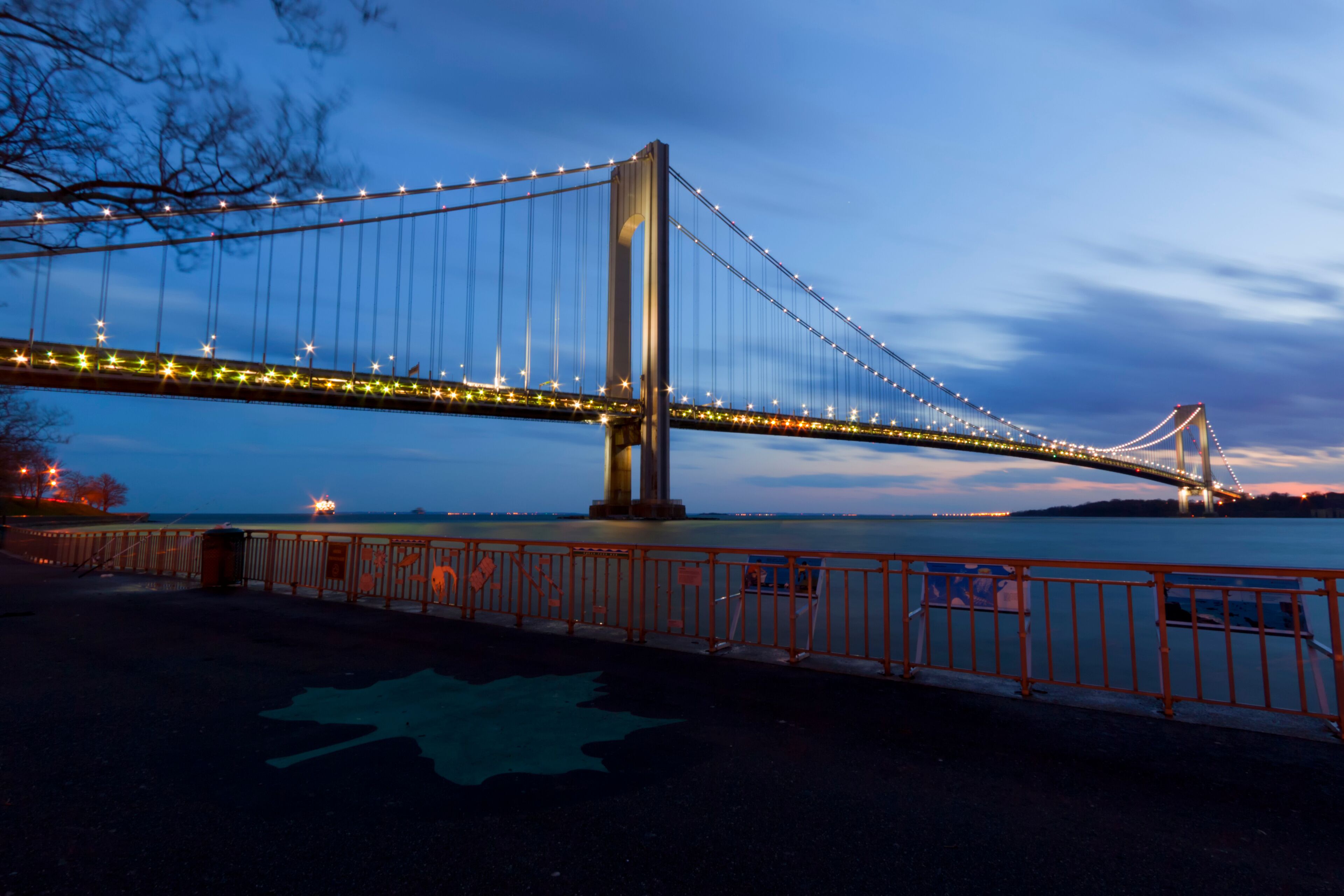 Un gran puente colgante al anochecer, con cables iluminados y un diseño en forma de estrella en el suelo.