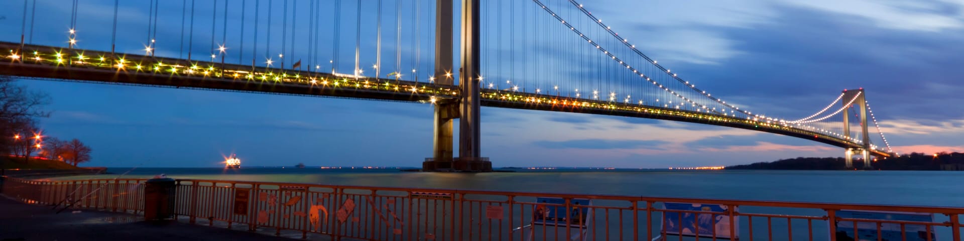 Un gran puente colgante al anochecer, con cables iluminados y un diseño en forma de estrella en el suelo.