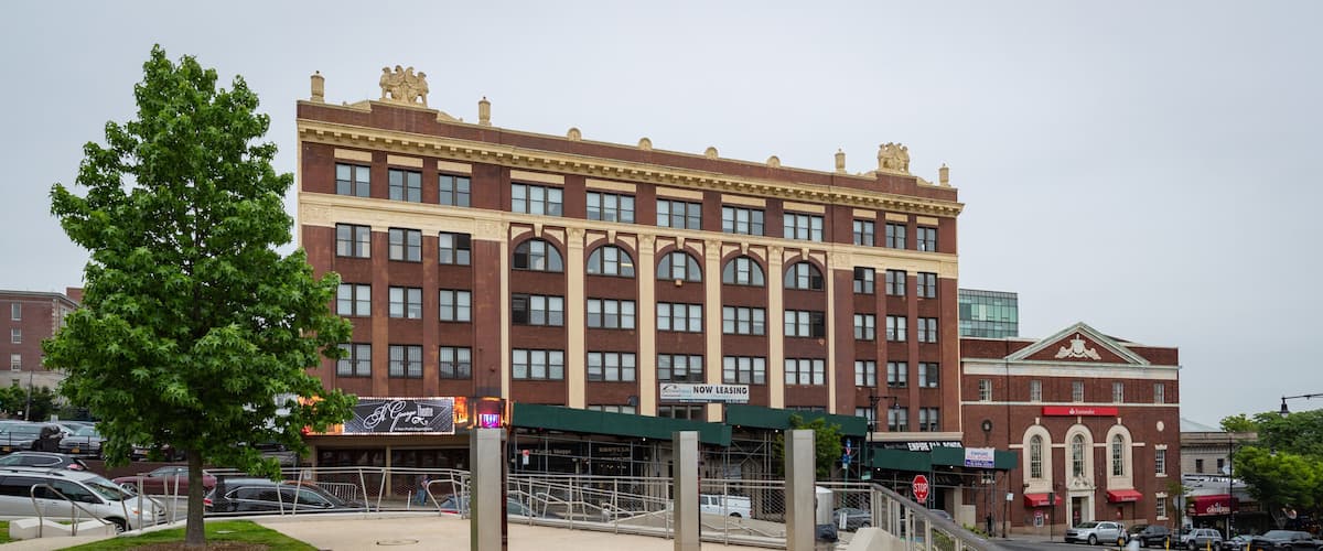 A large brick building with arched windows and a green awning.