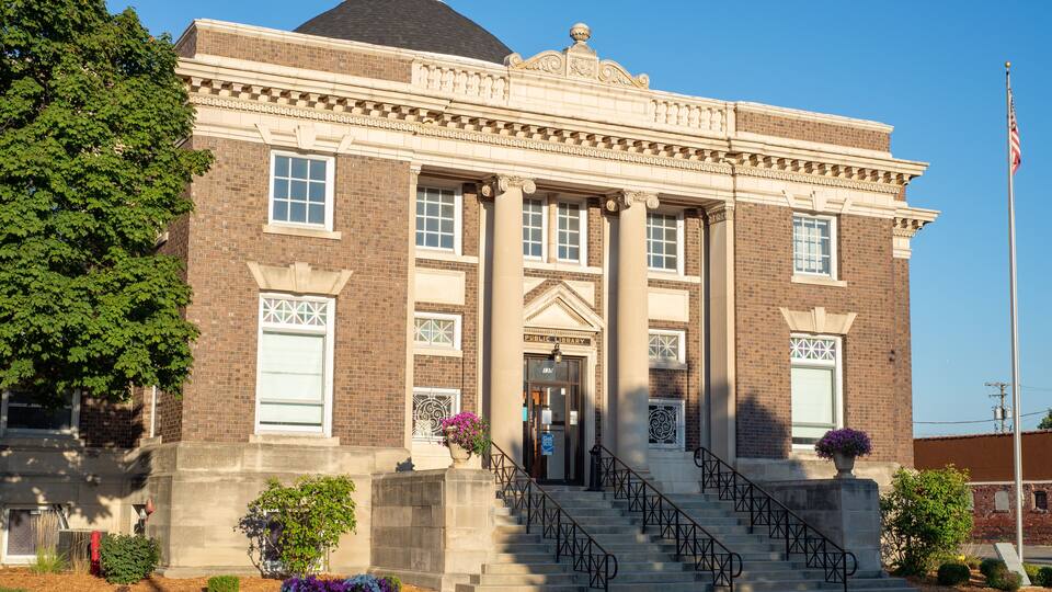 A brick building with a dome, columns, and a flagpole.