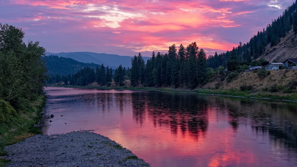 The sun sets over the Clark Fork River in the town of Superior, Montana, USA
