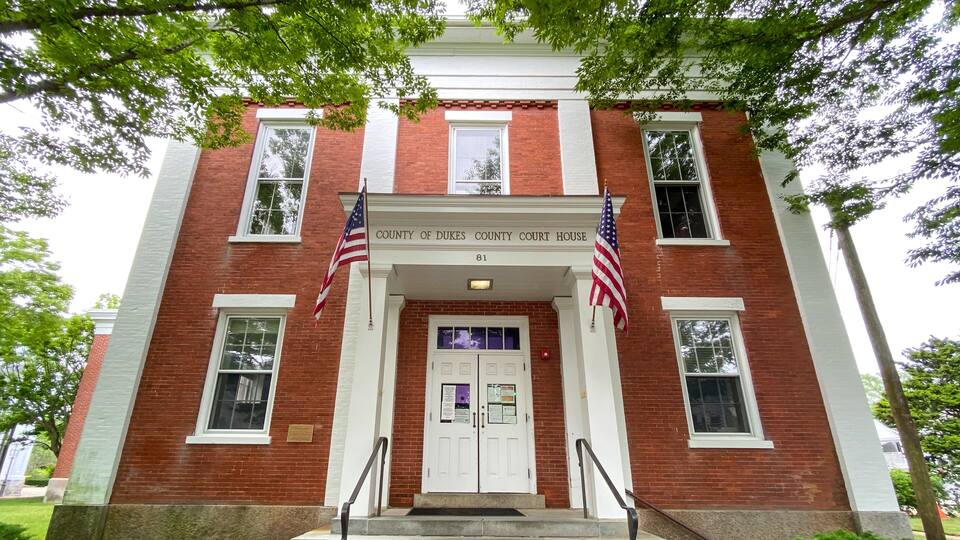A red brick courthouse with two American flags and a white door.