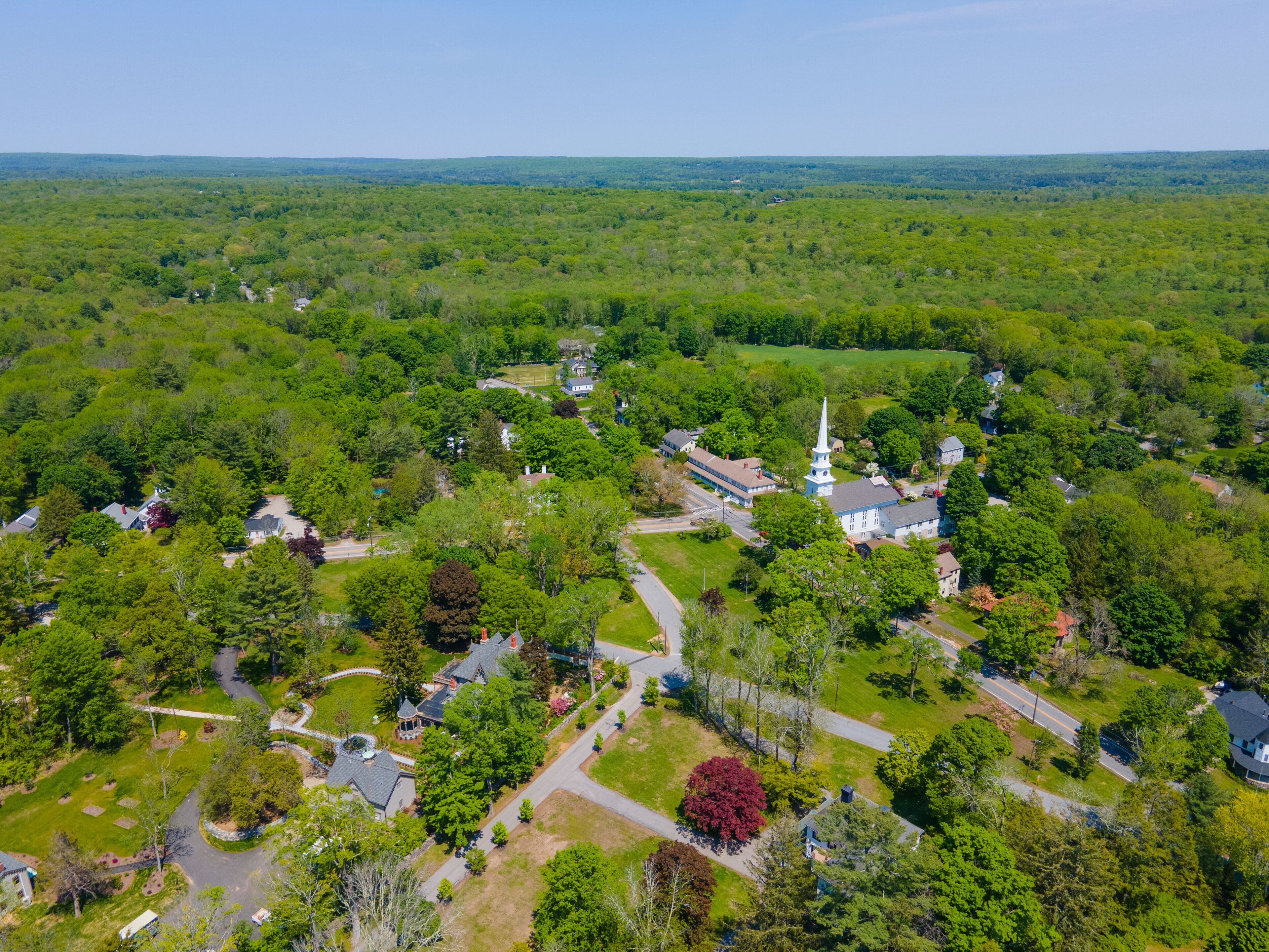 A lush green landscape with a prominent church featuring a tall steeple.